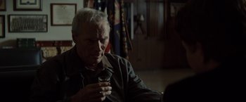 Movie still from “Gran Torino” (2008), directed by Clint Eastwood – An older man is holding a glass of wine; Close Up shot, Over the shoulder angle