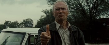 Movie still from “Gran Torino” (2008), directed by Clint Eastwood – An older man giving a thumbs up sign; Close Up shot, Low angle