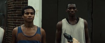 Movie still from “Gran Torino” (2008), directed by Clint Eastwood – Two young men standing next to each other holding a gun; Medium shot, Low angle