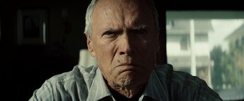Movie still from “Gran Torino” (2008), directed by Clint Eastwood – An older man with a frowning look on his face; Close Up shot, Low angle