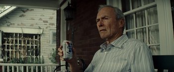 Movie still from “Gran Torino” (2008), directed by Clint Eastwood – An older man holding a can of beer in front of a brick wall; Close Up shot, Low angle