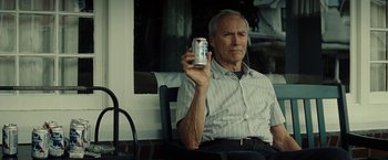 Movie still from “Gran Torino” (2008), directed by Clint Eastwood – An older man sitting in a chair holding a can of soda; Medium shot, Low angle