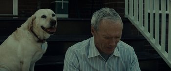 Movie still from “Gran Torino” (2008), directed by Clint Eastwood – An older man and a dog are sitting next to each other; Close Up shot, Over the shoulder angle