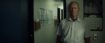Movie still from “Gran Torino” (2008), directed by Clint Eastwood – An older man standing in front of a wall; Medium shot, Low angle