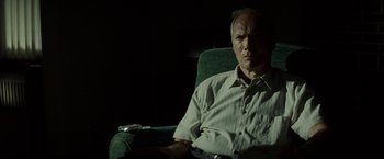 Movie still from “Gran Torino” (2008), directed by Clint Eastwood – An older man sitting in a chair in a dark room; Medium shot, Low angle
