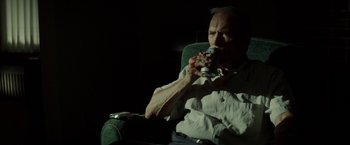 Movie still from “Gran Torino” (2008), directed by Clint Eastwood – An older man sitting in a chair eating a can of soda; Medium shot, Low angle