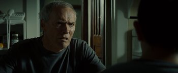 Movie still from “Gran Torino” (2008), directed by Clint Eastwood – An older man sitting at a table in front of a window; Close Up shot, Over the shoulder angle