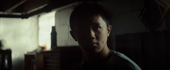 Movie still from “Gran Torino” (2008), directed by Clint Eastwood – A young man is looking into the camera; Close Up shot, Over the shoulder angle