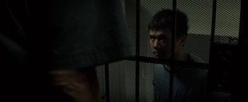 Movie still from “Gran Torino” (2008), directed by Clint Eastwood – A man standing behind a metal fence looking at another man; Close Up shot, Over the shoulder angle