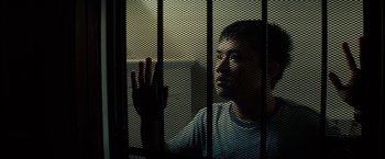 Movie still from “Gran Torino” (2008), directed by Clint Eastwood – A man is looking out of a jail cell through bars; Close Up shot, Low angle