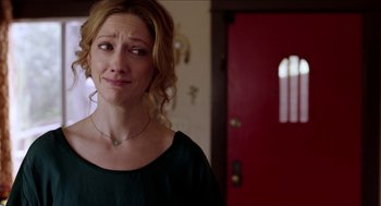 Movie still from “Grandma” (2015), directed by Paul Weitz – A person wearing a necklace near a door; Close Up shot, Over the shoulder angle