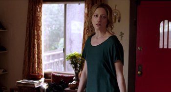 Movie still from “Grandma” (2015), directed by Paul Weitz – A woman standing in front of a window in a room; Medium shot, Over the shoulder angle