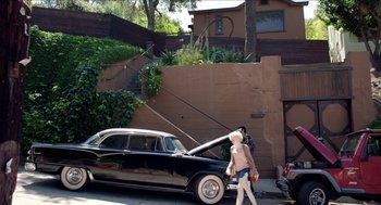 Movie still from “Grandma” (2015), directed by Paul Weitz – A woman walking past a parked car on the side of the road; Wide shot, High angle