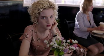 Movie still from “Grandma” (2015), directed by Paul Weitz – A woman sitting at a table with a bouquet of flowers in front of her face; Close Up shot, Over the shoulder angle