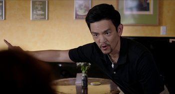 Movie still from “Grandma” (2015), directed by Paul Weitz – A man sitting at a table in front of a bottle of beer; Medium shot, Over the shoulder angle