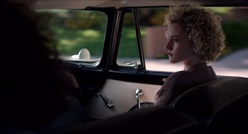 Movie still from “Grandma” (2015), directed by Paul Weitz – A woman sitting in the back seat of a car looking out the window; Medium shot, Over the shoulder angle