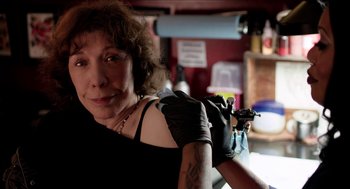 Movie still from “Grandma” (2015), directed by Paul Weitz – A woman in black shirt and black gloves holding a tattoo machine; Close Up shot, Low angle