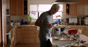 Movie still from “Grandma” (2015), directed by Paul Weitz – A man standing in a kitchen preparing a meal; Medium shot, Over the shoulder angle