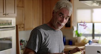 Movie still from “Grandma” (2015), directed by Paul Weitz – An older man in a gray t - shirt in a kitchen; Close Up shot, Over the shoulder angle