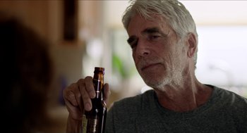 Movie still from “Grandma” (2015), directed by Paul Weitz – An older man holding a bottle of beer in his hand; Close Up shot, Over the shoulder angle