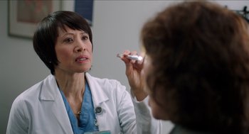 Movie still from “Grandma” (2015), directed by Paul Weitz – A woman in a white lab coat is holding an electronic device; Close Up shot, Over the shoulder angle