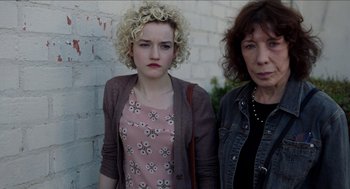 Movie still from “Grandma” (2015), directed by Paul Weitz – Two women standing next to each other in front of a brick wall; Close Up shot, High angle