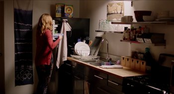 Movie still from “Grandma” (2015), directed by Paul Weitz – A woman in a kitchen holding a dish towel; Wide shot, Over the shoulder angle