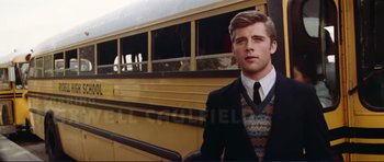 Movie still from “Grease 2” (1982), directed by Patricia Birch – A man in a suit and tie standing in front of a school bus; Medium shot, Over the shoulder angle