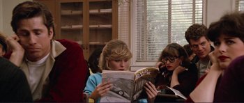 Movie still from “Grease 2” (1982), directed by Patricia Birch – A woman sitting down reading a magazine in front of a window; Medium shot, High angle
