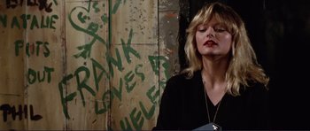 Movie still from “Grease 2” (1982), directed by Patricia Birch – A woman standing in front of a wall with graffiti on it; Medium shot, Low angle