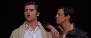 Movie still from “Grease 2” (1982), directed by Patricia Birch – Two young men standing next to each other; Close Up shot, Over the shoulder angle
