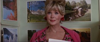 Movie still from “Grease 2” (1982), directed by Patricia Birch – A person wearing a dress with a picture on the wall in the background; Close Up shot, Over the shoulder angle
