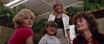 Movie still from “Grease 2” (1982), directed by Patricia Birch – A group of women standing next to each other in a room; Medium shot, Low angle