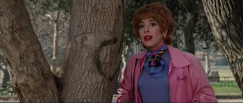 Movie still from “Grease 2” (1982), directed by Patricia Birch – A woman in a pink jacket standing next to a tree; Medium shot, Over the shoulder angle