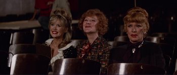 Movie still from “Grease 2” (1982), directed by Patricia Birch – Two women are sitting in a row of chairs; Medium shot, Low angle