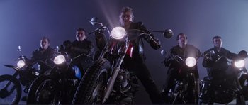 Movie still from “Grease 2” (1982), directed by Patricia Birch – A group of people riding motorcycles at night time; Wide shot, Low angle