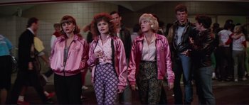 Movie still from “Grease 2” (1982), directed by Patricia Birch – A group of people standing next to each other wearing pink jackets; Medium shot, High angle