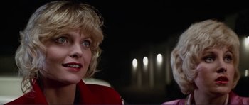 Movie still from “Grease 2” (1982), directed by Patricia Birch – Two women sitting next to each other in a dark room; Close Up shot, Over the shoulder angle