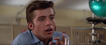 Movie still from “Grease 2” (1982), directed by Patricia Birch – A young man is sitting in front of a glass; Close Up shot, Over the shoulder angle