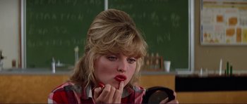 Movie still from “Grease 2” (1982), directed by Patricia Birch – A woman is putting lipstick on in front of a chalkboard; Close Up shot, Low angle