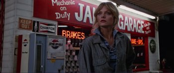 Movie still from “Grease 2” (1982), directed by Patricia Birch – A woman standing in front of a building with a neon sign; Medium shot, Low angle