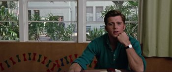 Movie still from “Grease 2” (1982), directed by Patricia Birch – A man sitting at a table with his hand under his chin; Medium shot, Over the shoulder angle
