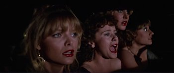 Movie still from “Grease 2” (1982), directed by Patricia Birch – A group of women standing next to each other in a dark room; Close Up shot, Low angle