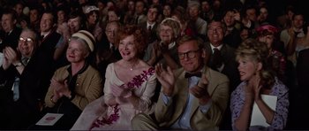 Movie still from “Grease 2” (1982), directed by Patricia Birch – A group of people sitting and clapping in front of a crowd; Medium shot, Over the shoulder angle