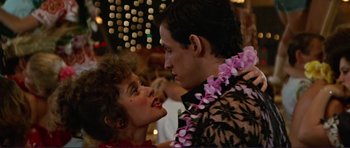 Movie still from “Grease 2” (1982), directed by Patricia Birch – A man and a woman wearing hawaiian leis; Close Up shot, Over the shoulder angle