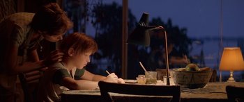 Movie still from “Great Expectations” (1998), directed by Alfonso Cuarón – A person sitting at a table writing on a piece of paper; Medium shot, Low angle