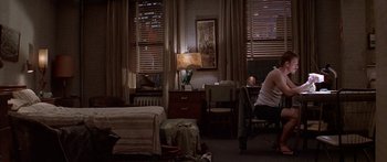 Movie still from “Great Expectations” (1998), directed by Alfonso Cuarón – A man sitting on a chair in front of a bed; Wide shot, High angle