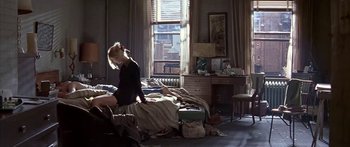 Movie still from “Great Expectations” (1998), directed by Alfonso Cuarón – A woman sitting on top of a bed next to a desk; Wide shot, High angle