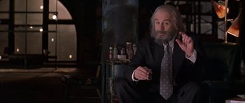 Movie still from “Great Expectations” (1998), directed by Alfonso Cuarón – An older man sitting in a chair holding a glass of wine; Medium shot, Over the shoulder angle