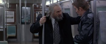 Movie still from “Great Expectations” (1998), directed by Alfonso Cuarón – An older man with a long gray beard is on a train; Medium shot, Over the shoulder angle